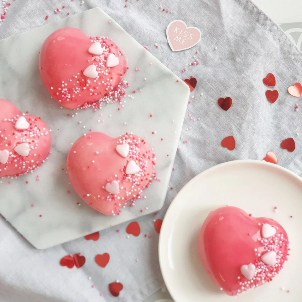 Moussebakelser i form av hjärtan med rosa glaze och strössel